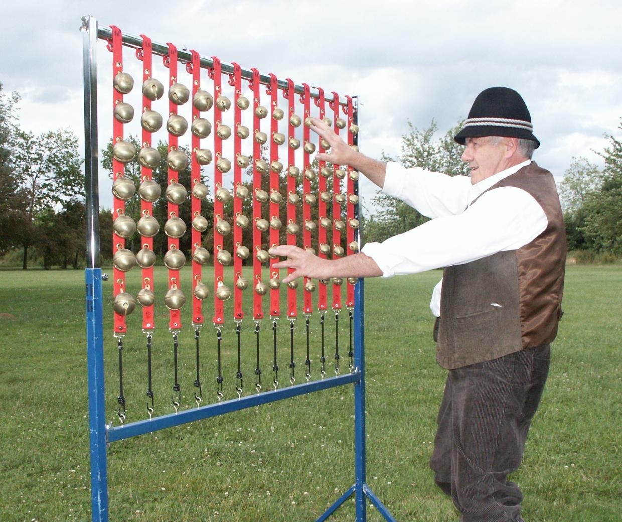 L’un de nous joue sur un portique de grelots de laiton monté sur un cadre rouge, en plein air